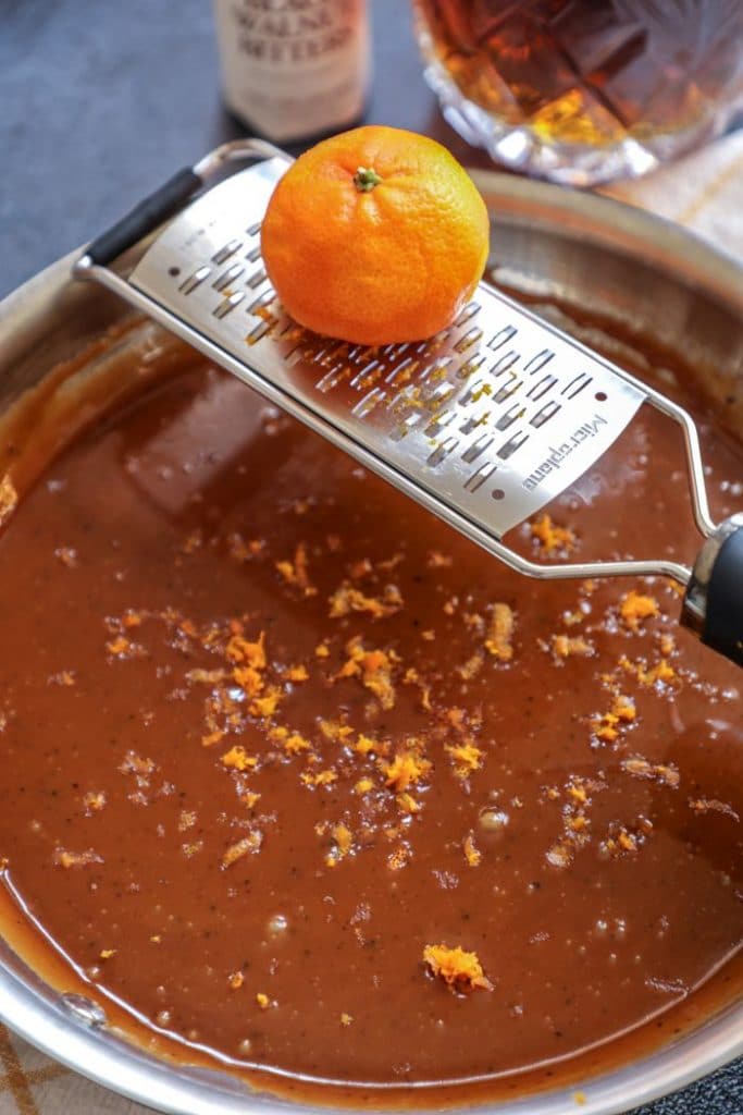 Orange being zested into the caramel