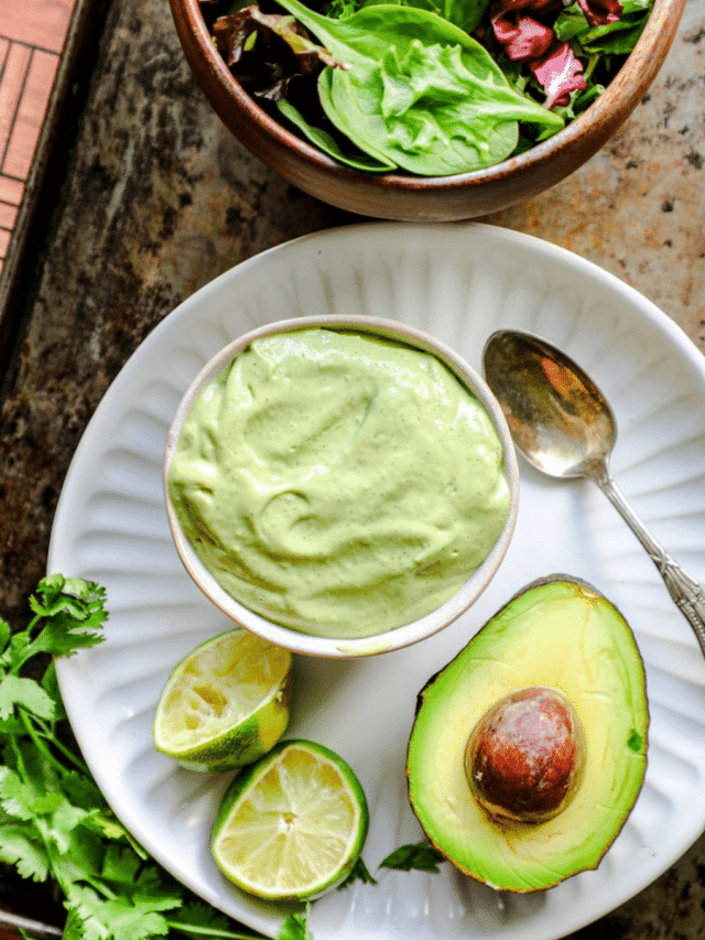 Avocado dressing in a bowl on a tray with an avocado next to it