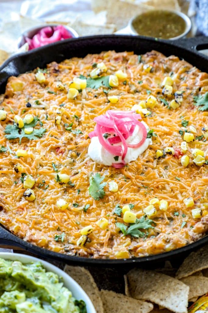 Fiesta Corn Dip in a cast iron pan with tortilla chips