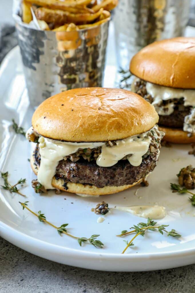 Mushroom Duxelles Burger on a white plate with sprigs of thyme on it.